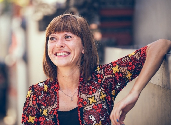 Woman smiling and leaning against a wall